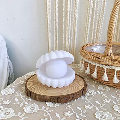 Decorative lamp with a shell design on a wooden base, placed on a lace tablecloth.