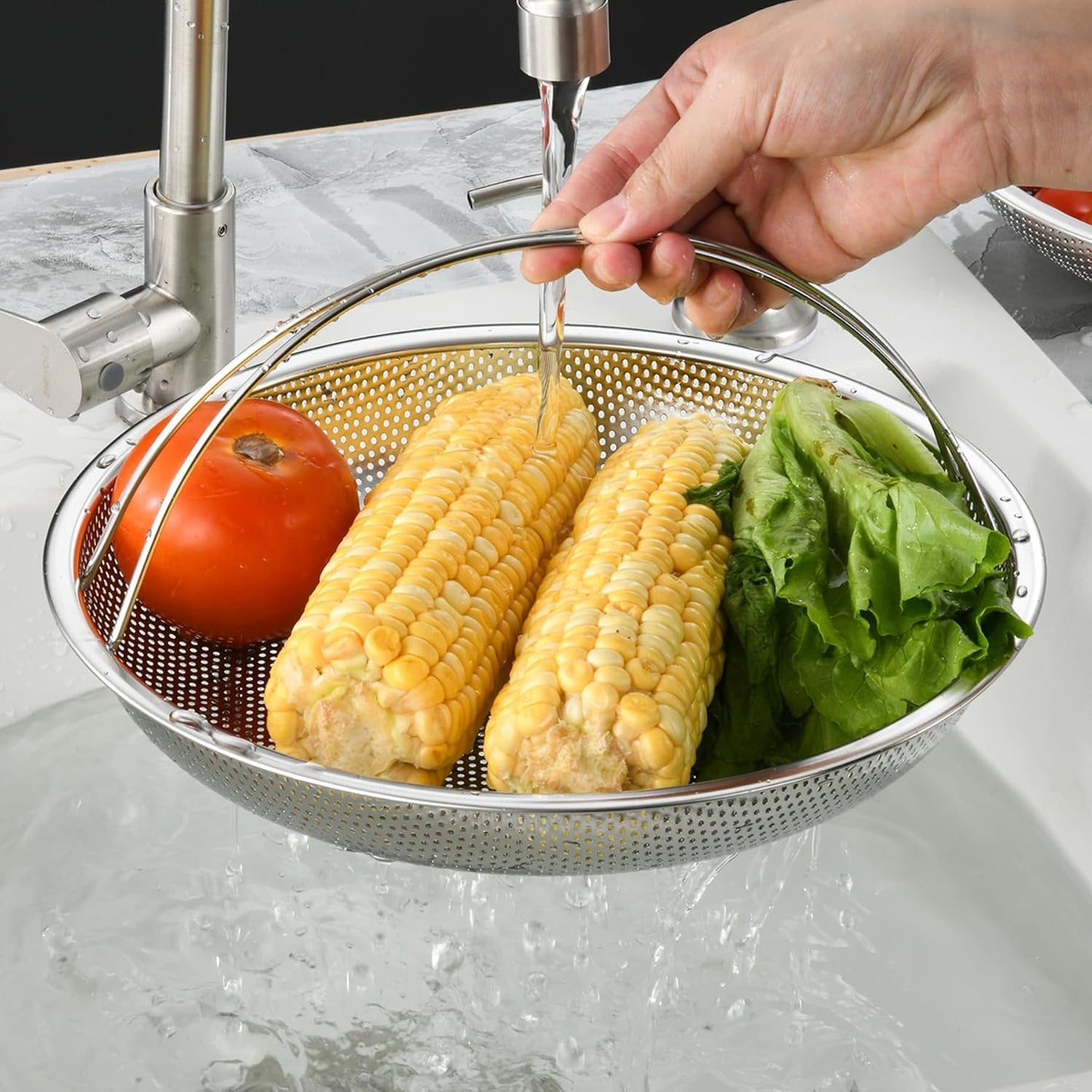 Person washing corn on the cob and lettuce in a colander under running water.