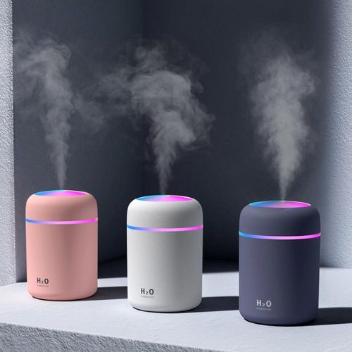 Three H2O humidifiers in pink, white, and black emitting steam against a dark background.