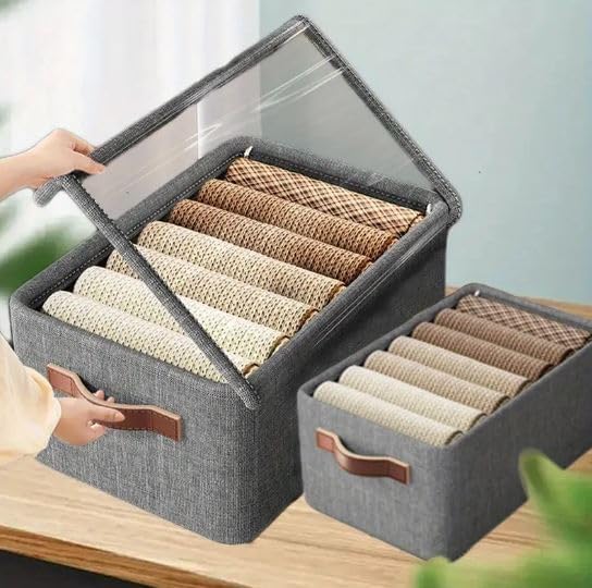 Gray storage box with transparent lid containing rolled-up fabrics on a wooden surface.