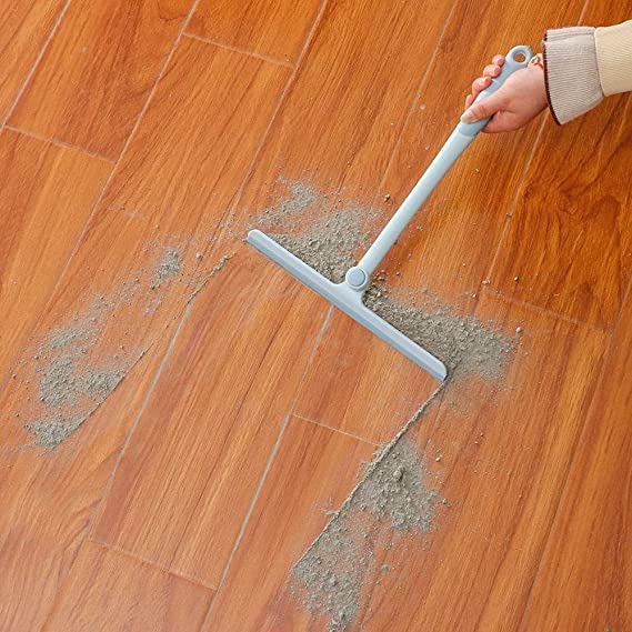 Person using a squeegee to clean grout on a wooden floor