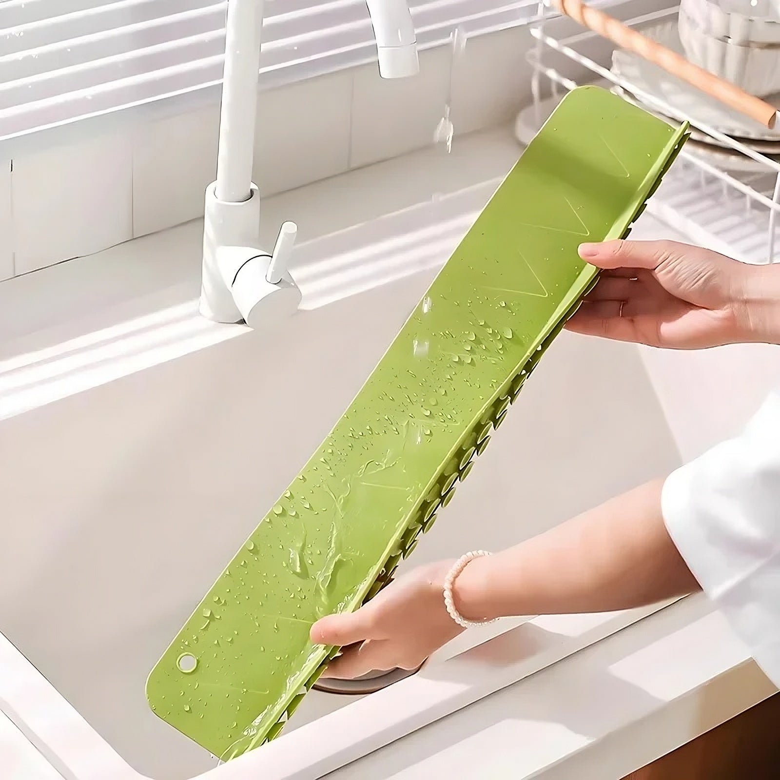 Green cutting board with water droplets held over a sink