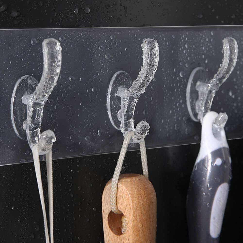 Clear suction cup hooks on a black surface with a wooden hook and white item.