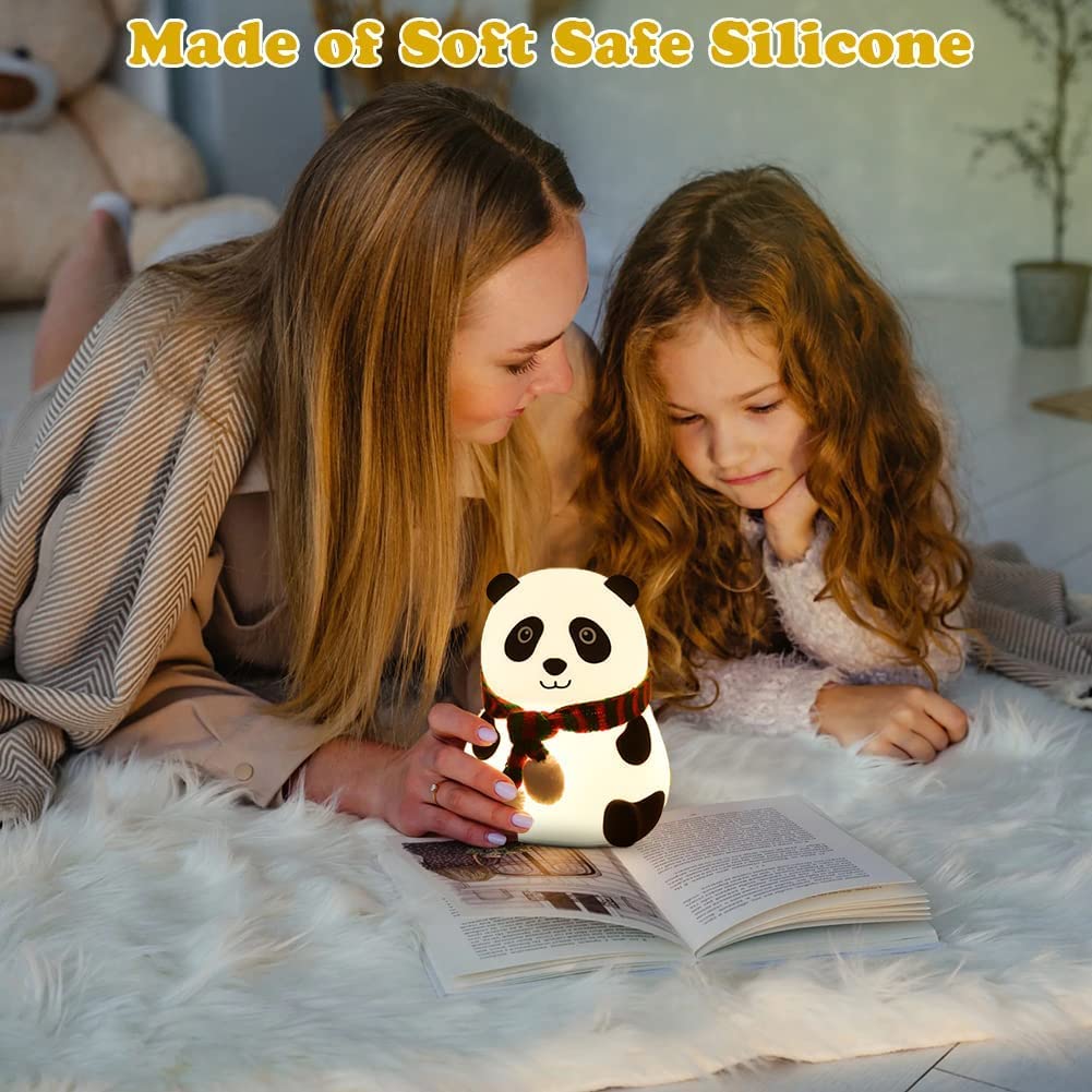 Woman and child reading a book with a panda-shaped night light on a soft surface.