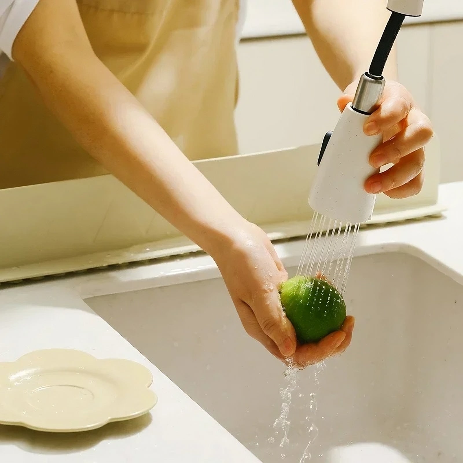 Person washing a green apple under a faucet in a kitchen sink.