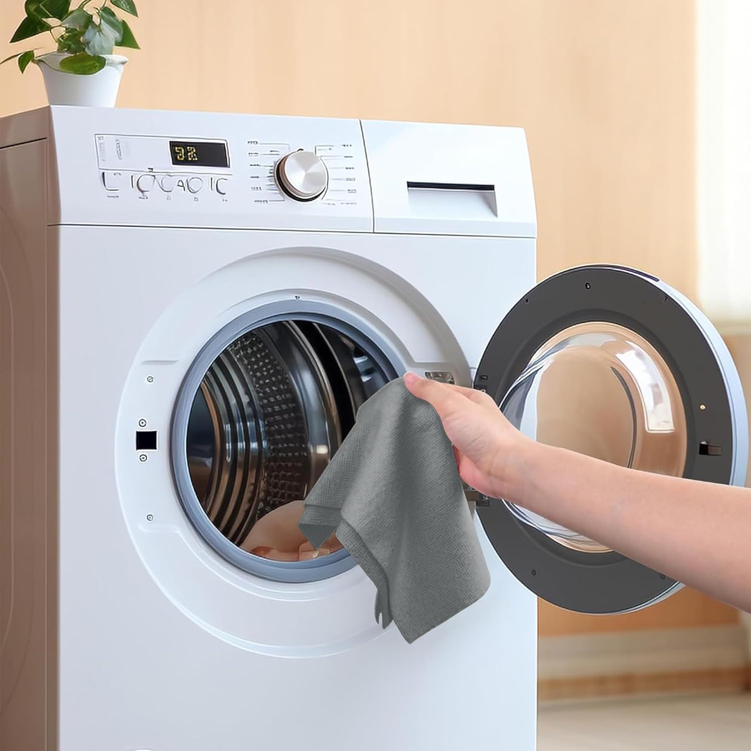 Person cleaning a white washing machine with a gray cloth.