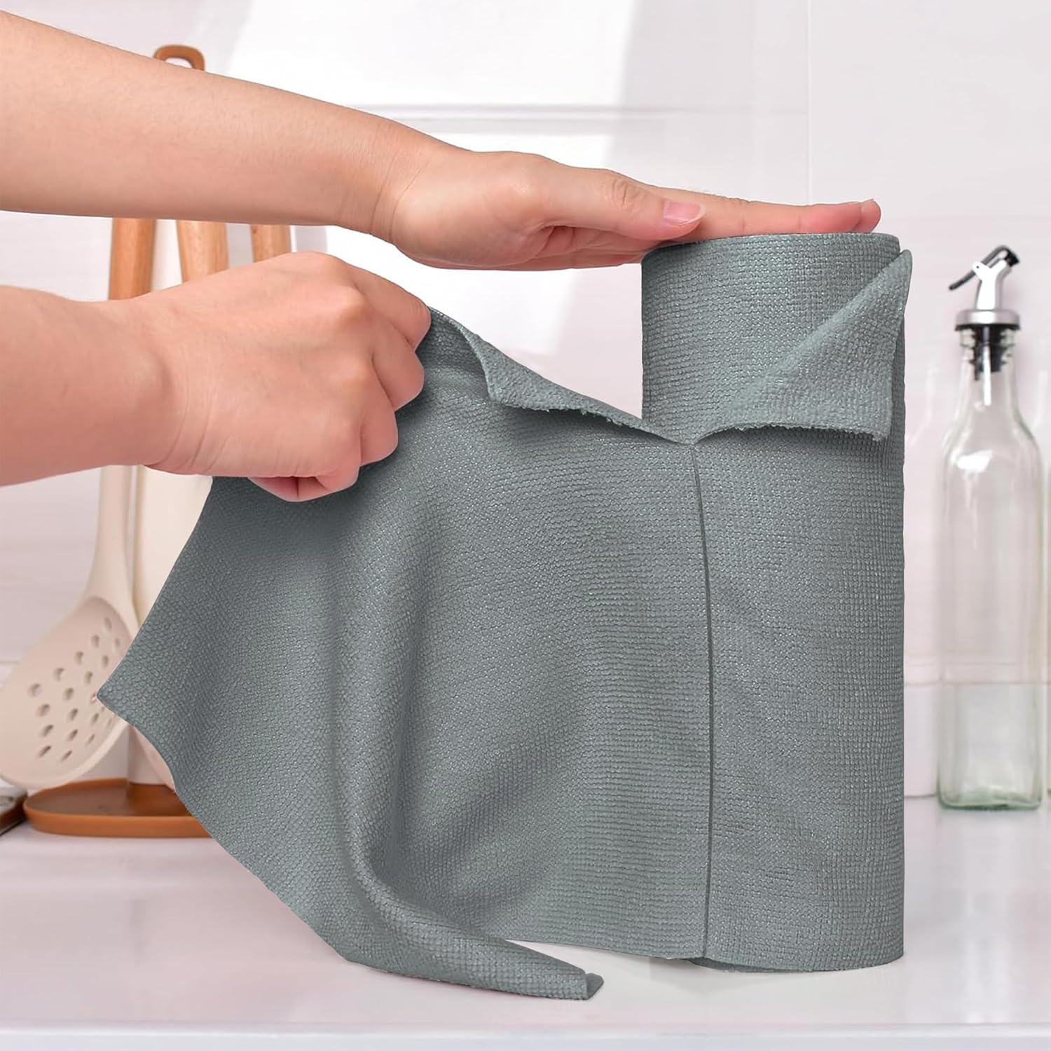 Person holding a gray kitchen towel with a kitchen background